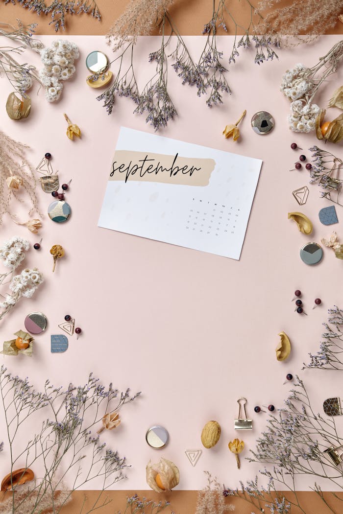 Aesthetic flatlay of a September calendar surrounded by dried flowers and decorative elements.